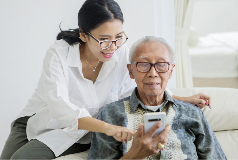Elderly man using a phone with his daughter.