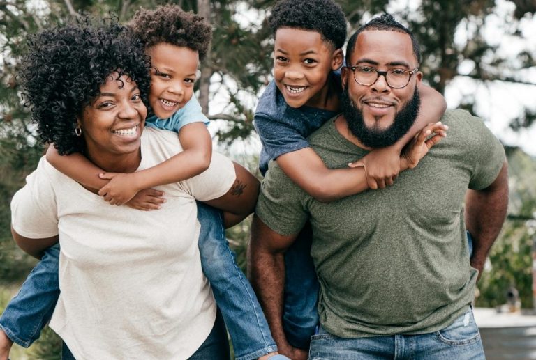 Family of a mother, father, and two kids smiling outside