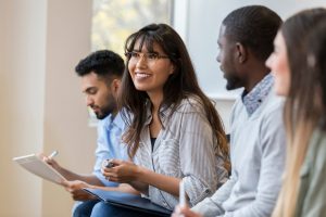 Four employees sitting down in a meeting taking notes.